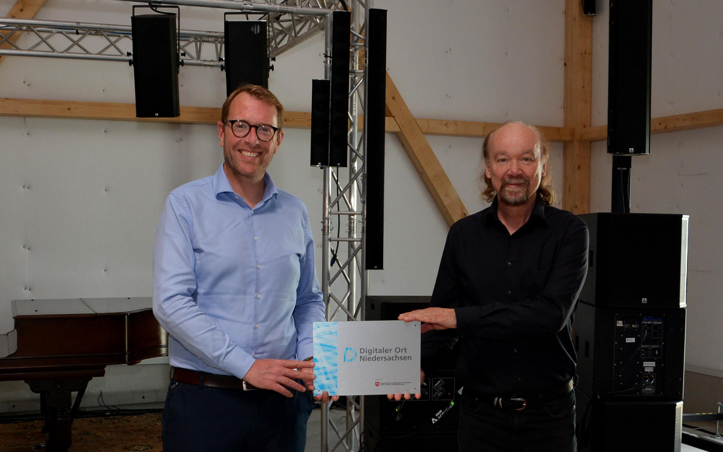 Staatssekretär Stefan Muhle überreicht Udo Borgmann die Pakette mit der Auszeichnung "Digitaler Ort Niedersachsen"