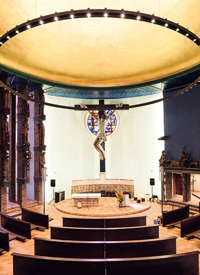 Blick vom Ende des Kirchenraums in St. Bonifatius auf den Altarraum, in dem eine Jesusfigur am Holzkreuz das Zentrum ausmacht.  