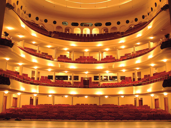 Der Theatersaal des Großen Hauses im Staatstheater Braunschweig mit Blick von der Bühne auf den leeren, angenehm beleuchteten Saal mit Parkett und drei Rängen.