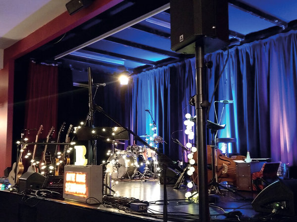 Die Bühne des Kulturortes "Roter Saal" im Braunschweiger Schloss. Auf der Bühne stehen Instrumente für ein Konzert bereit. Im Vordergrund steht der Lautsprecher P 261-AMT | Cine auf einem Stativ, der mit einer AMT-Hochtoneinheit von Mundorf versehen ist.
